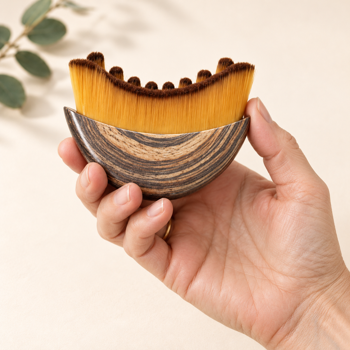 A hand holding the face brush, showing its real size and soft bristles